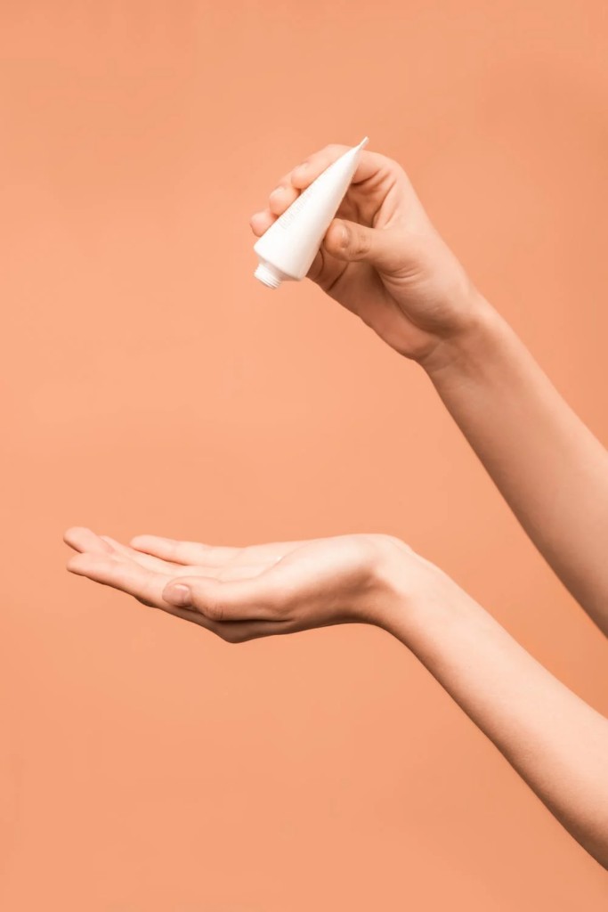 A woman squeezes a small tube containing luxury skincare.