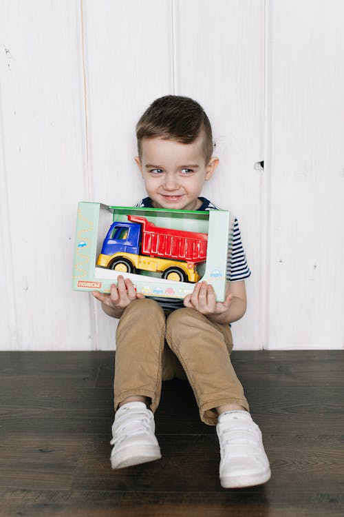 a little boy holding toy truck box