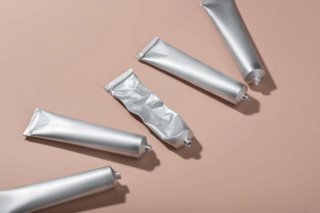 Multiple aluminum tubes, with one squeezed.