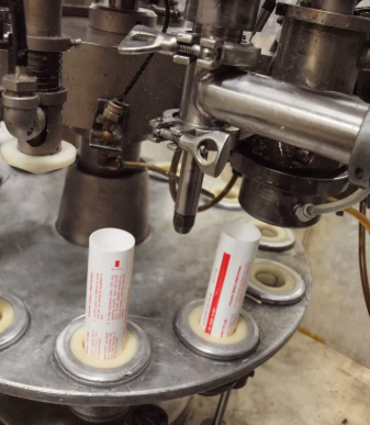 A person filling tubes with a machine.