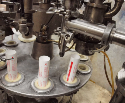 Several tubes being filled with a machine.