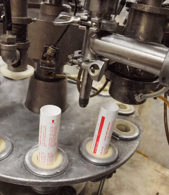 Several tubes being filled with a machine.